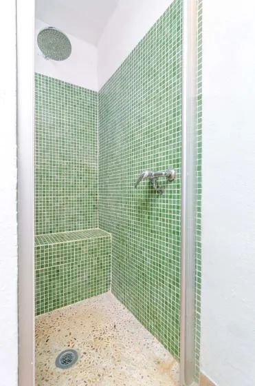 A tiled shower with green walls and a round overhead showerhead.