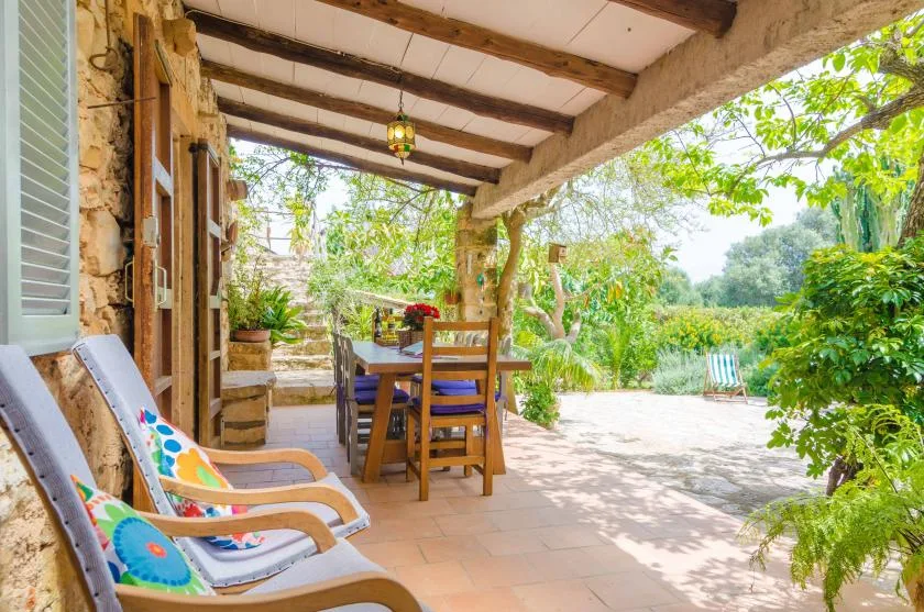 A covered outdoor dining area with a wooden table and colorful seating.