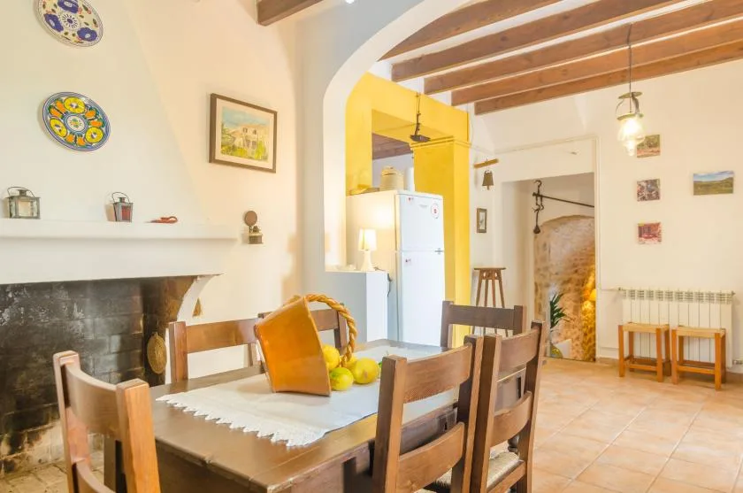 A dining area with a wooden table and chairs beside a fireplace.