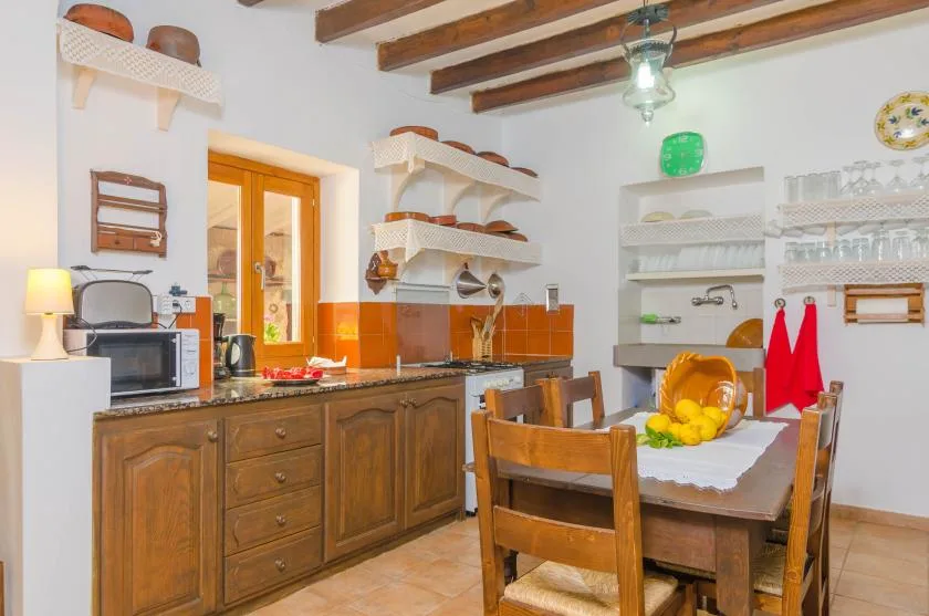 A rustic kitchen with wooden cabinets, open shelves, and a dining table.