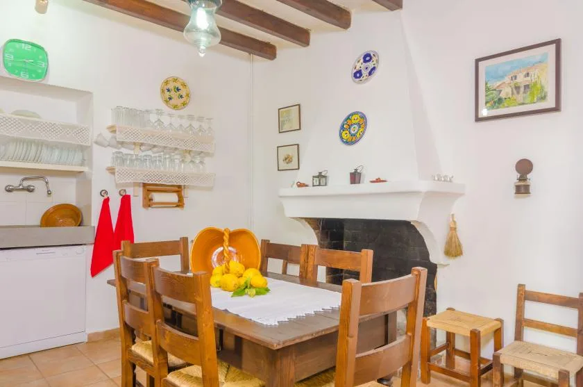 A dining area with a wooden table and chairs beside a fireplace.