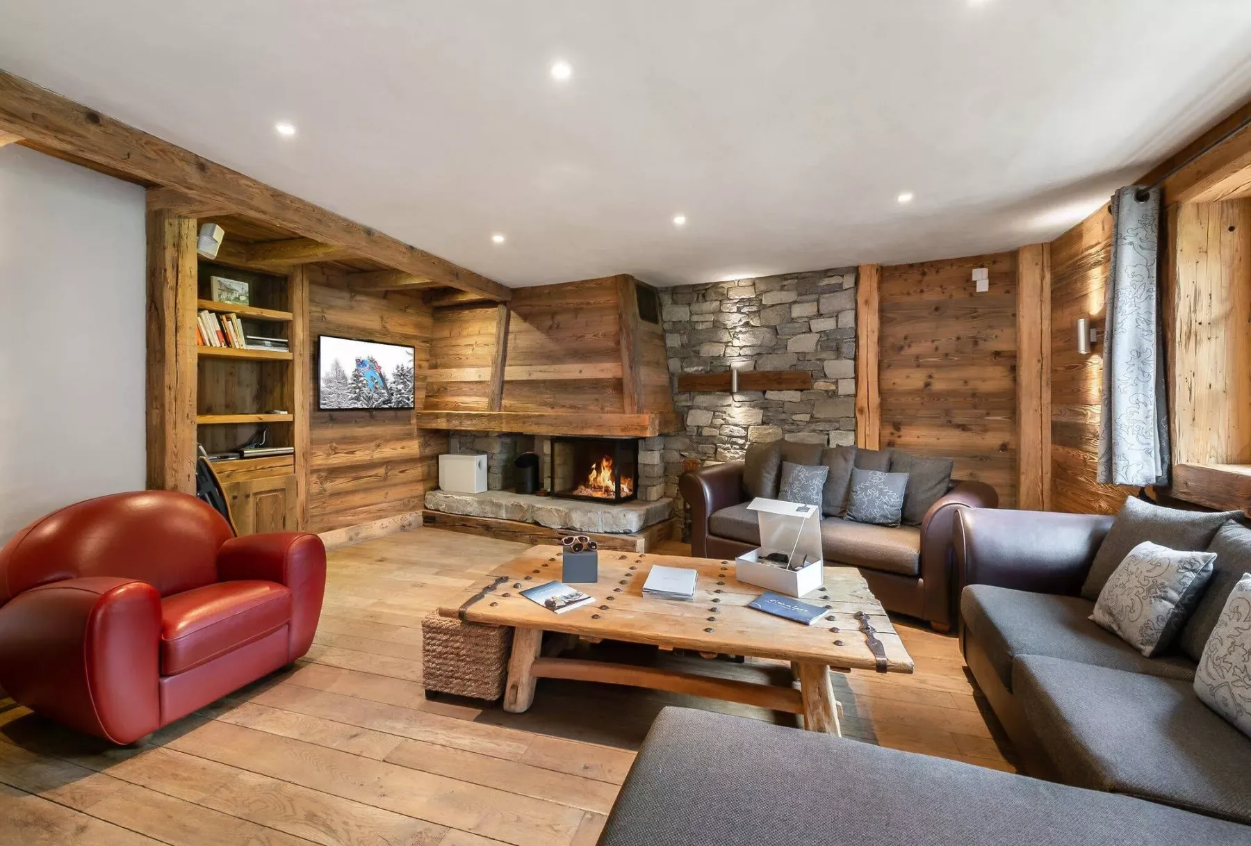 A wood-paneled living room with seating arranged around a low coffee table and fireplace.