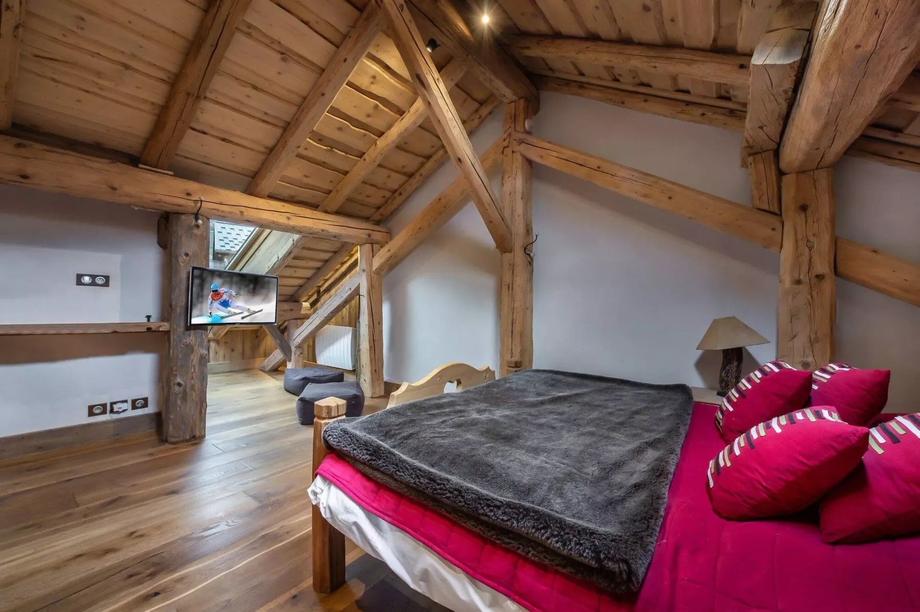 A bedroom with a bed dressed in a dark blanket and bright pink bedding.