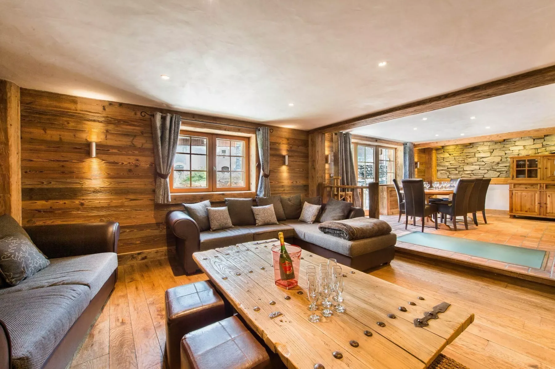 A wood-paneled living room with seating and a dining area beyond.