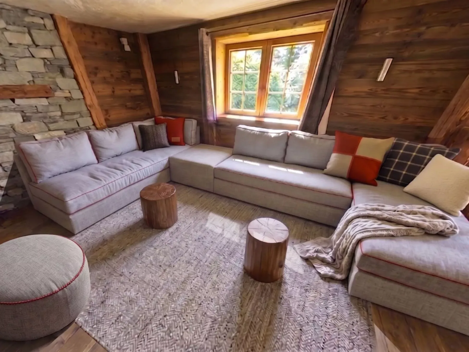 A wood-paneled living room has sectional seating around a woven rug.