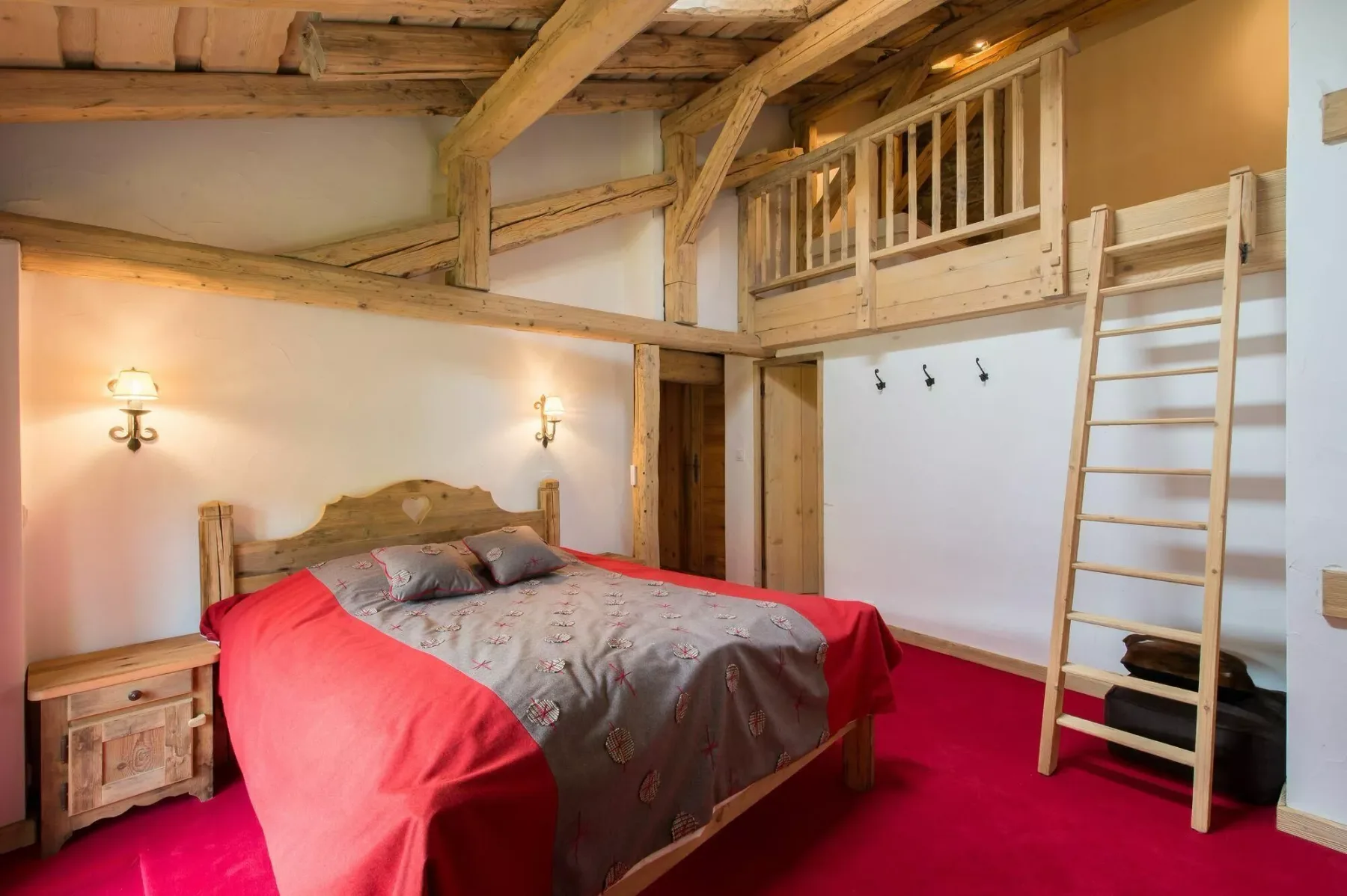 A bedroom with a large bed and a wooden loft above.