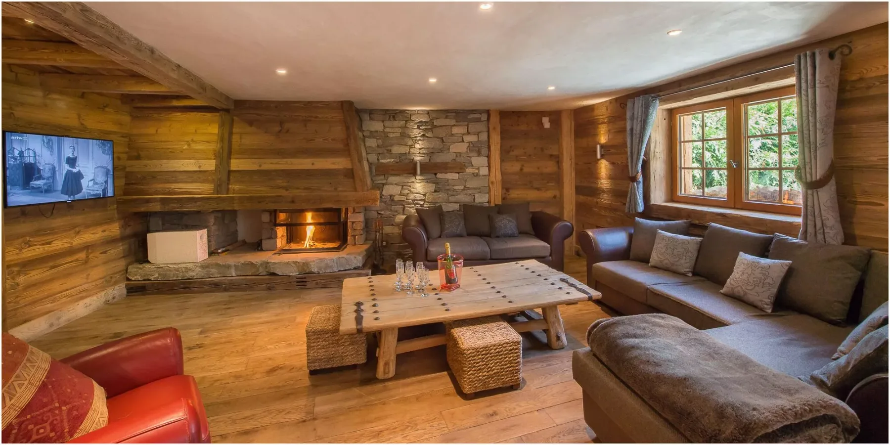 A rustic living room with wood-paneled walls, seating, and a central coffee table.