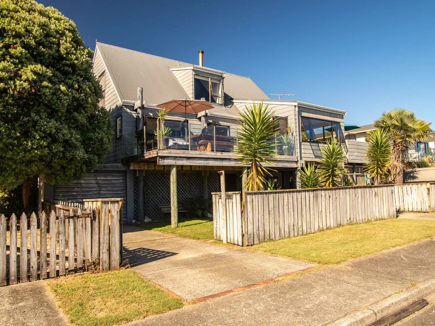 A two-story house with a wooden fence a balcony and trees at Pohara Beach Escape Pohara Beach