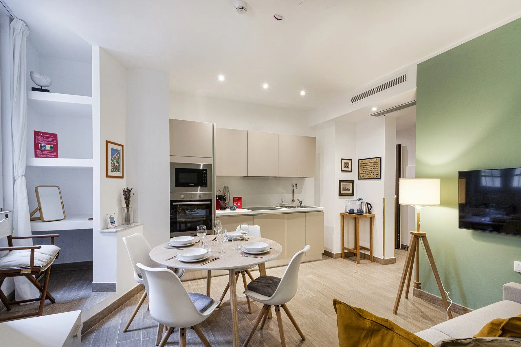 Un comedor con una mesa redonda está junto a una cocina compacta y una sala de estar.