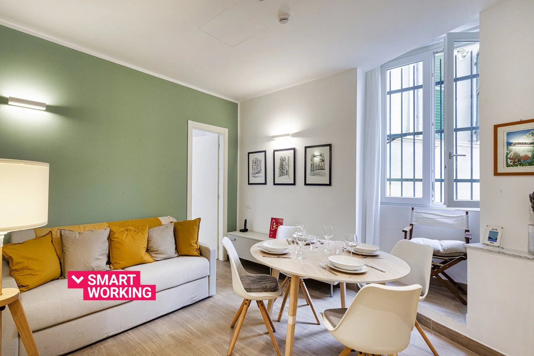 Sala de estar y comedor con sofá, mesa de comedor y ventanas altas.