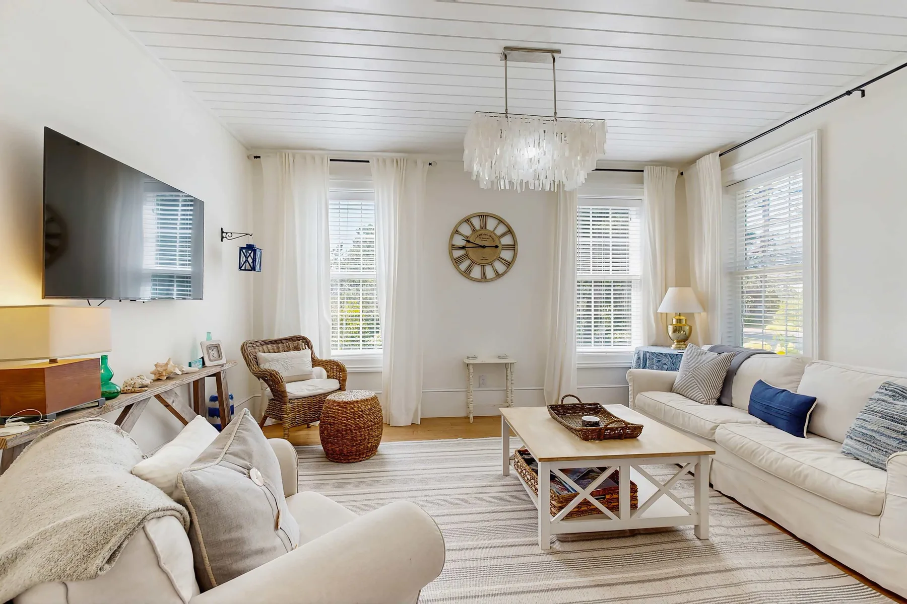 A bright living room with seating arranged around a coffee table and wall-mounted television.