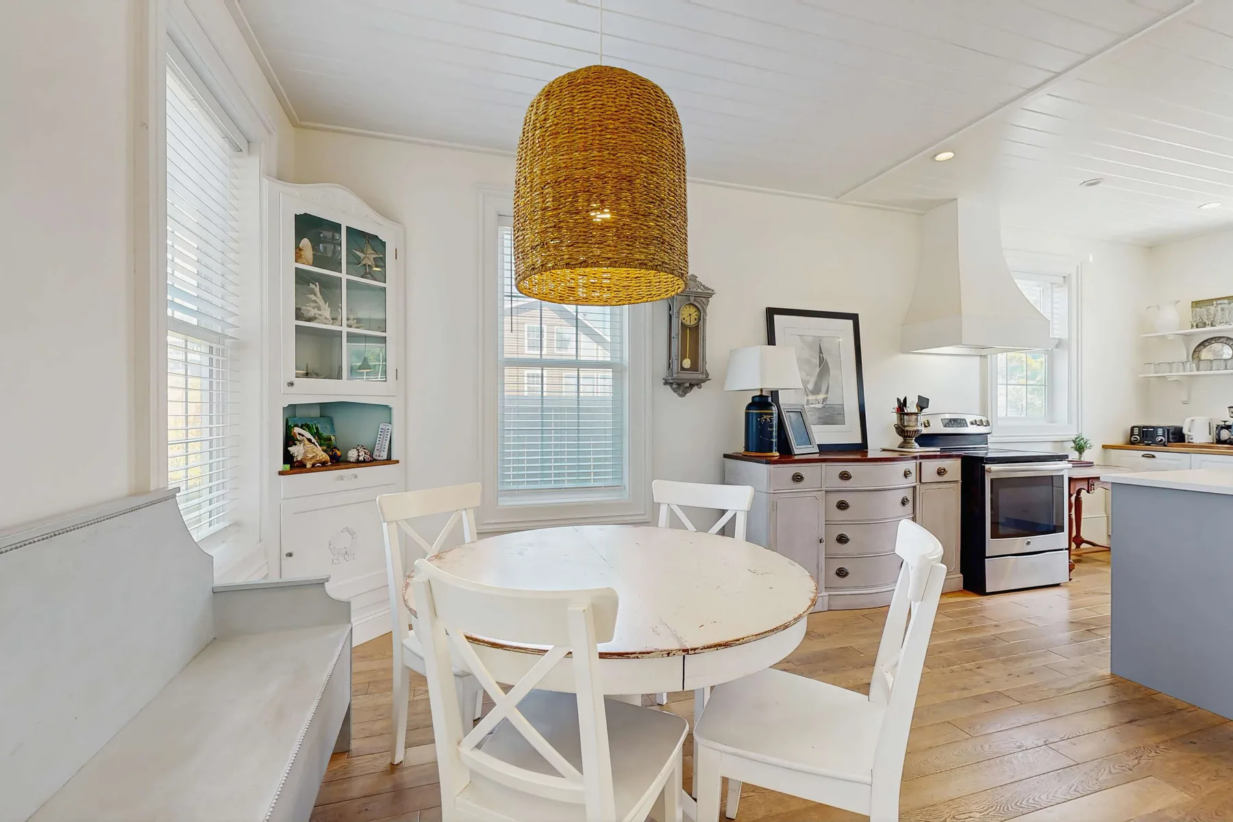 A bright dining area with a round table beneath a woven pendant light.