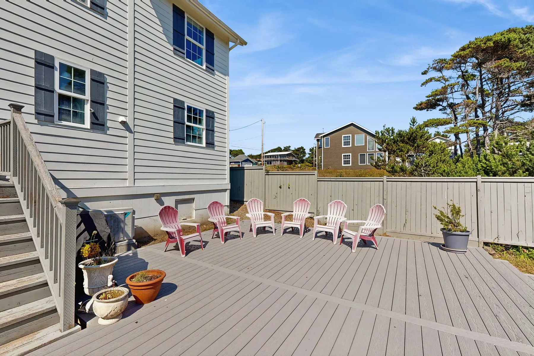 An outdoor deck with pink seating and a fenced yard.