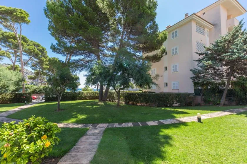 A landscaped lawn with trees and a paved path beside a residential building.