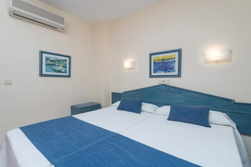 A bedroom with a bed dressed in white and blue linens.