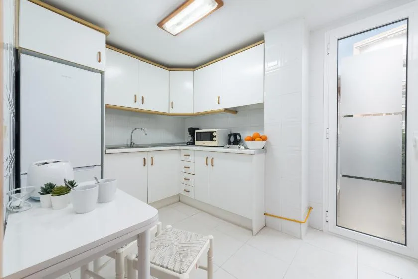 A bright white kitchen with a dining table and countertop appliances.
