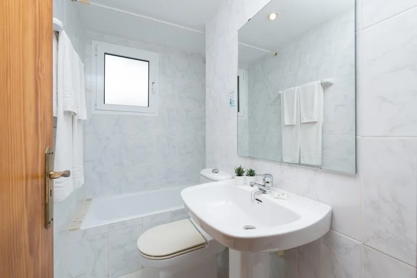 A bright bathroom with a bathtub, sink, and mirror.