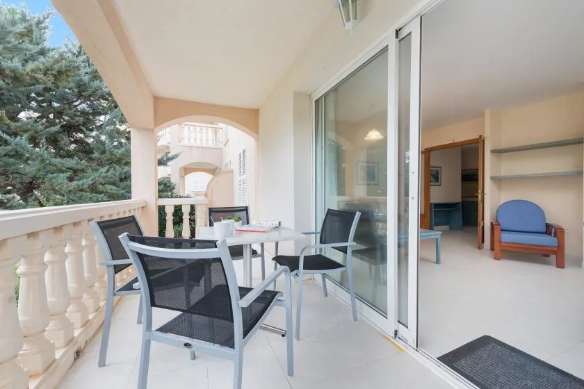 A covered balcony with outdoor seating overlooks nearby trees.