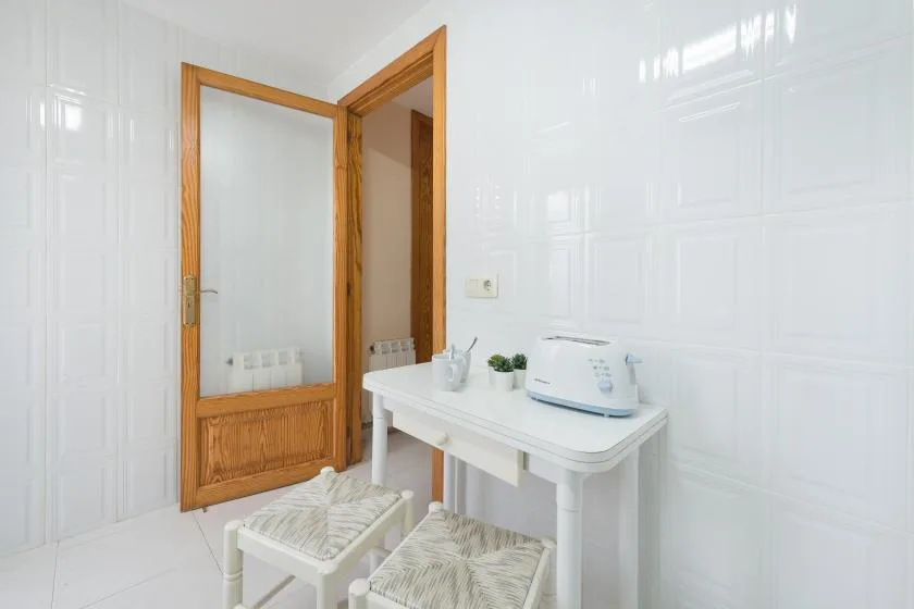 A tiled bathroom with a white vanity and an open wooden door.