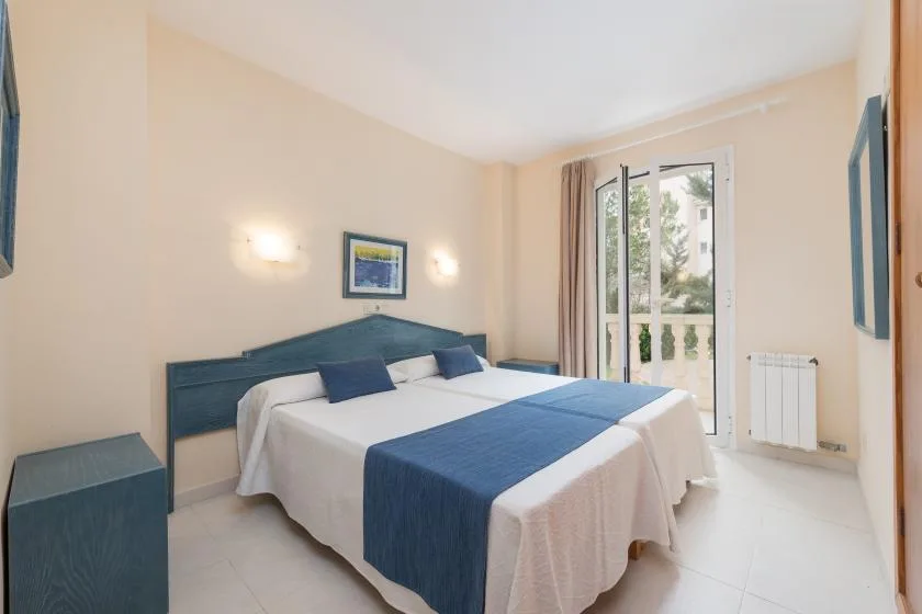 A bedroom with two beds dressed in white and blue linens.