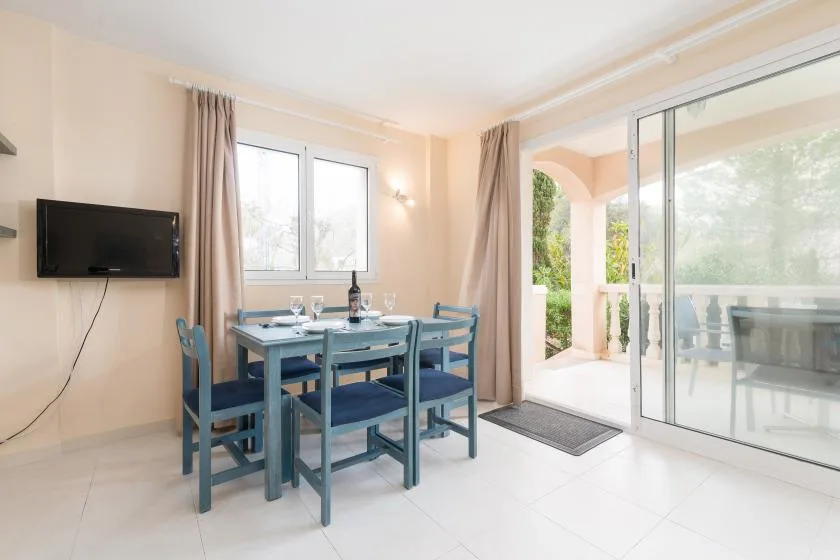 A dining area with a blue table and chairs beside large sliding glass doors.