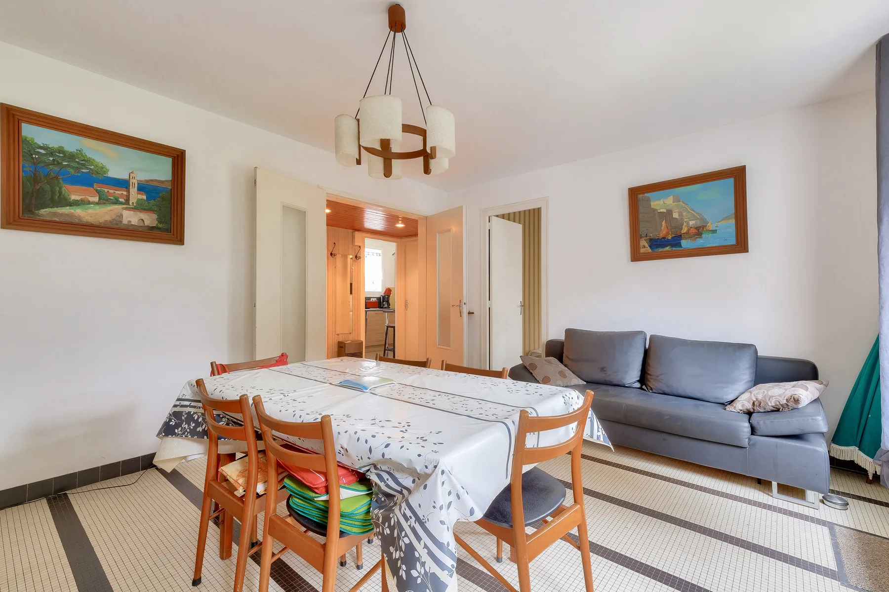 Dining area with a set table and seating beside a living area.