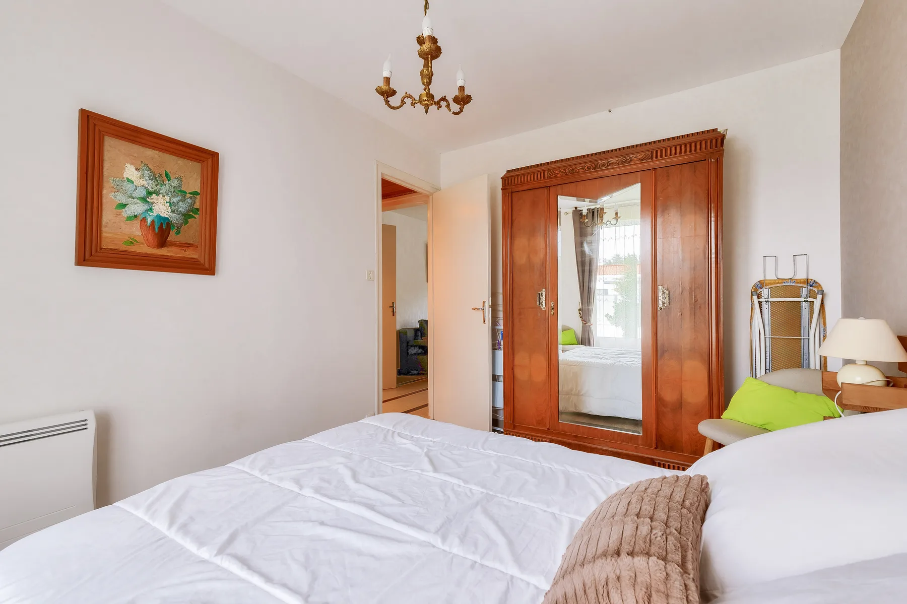 Bedroom with a bed, wooden wardrobe, and framed floral artwork.