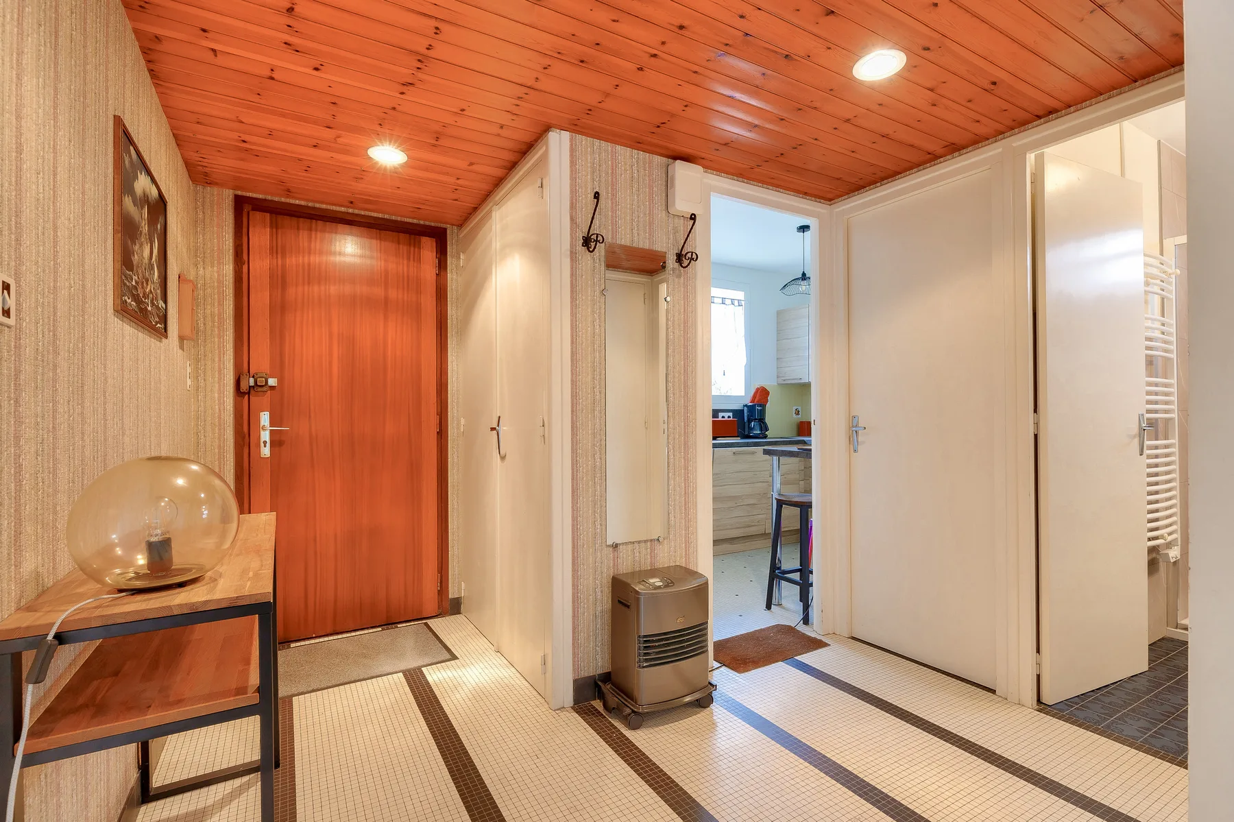 Entry hall with a wooden front door and a view into the kitchen.