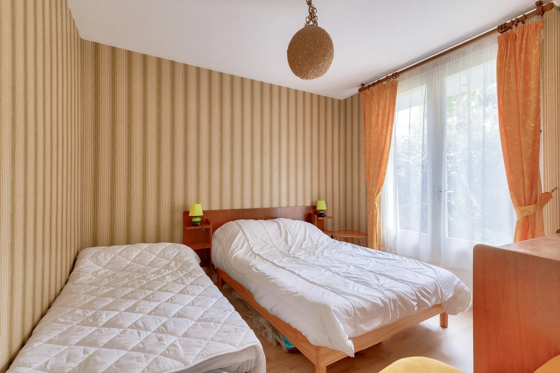 Bedroom with two beds and a large curtained window.