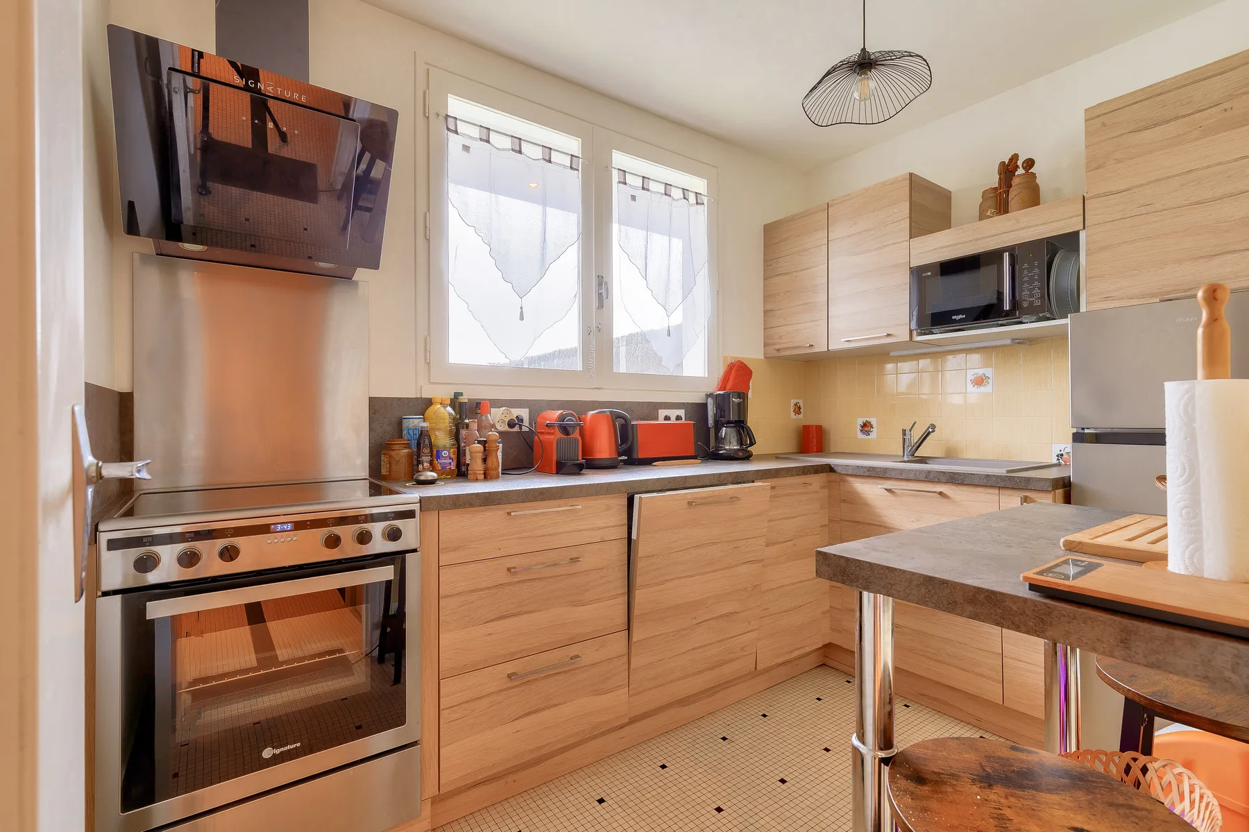 A bright kitchen with wood cabinetry, a stove, and a central island.