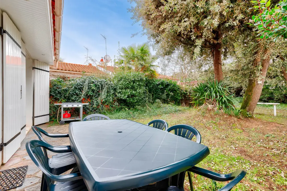 A garden patio with an outdoor dining table and chairs beside the house.