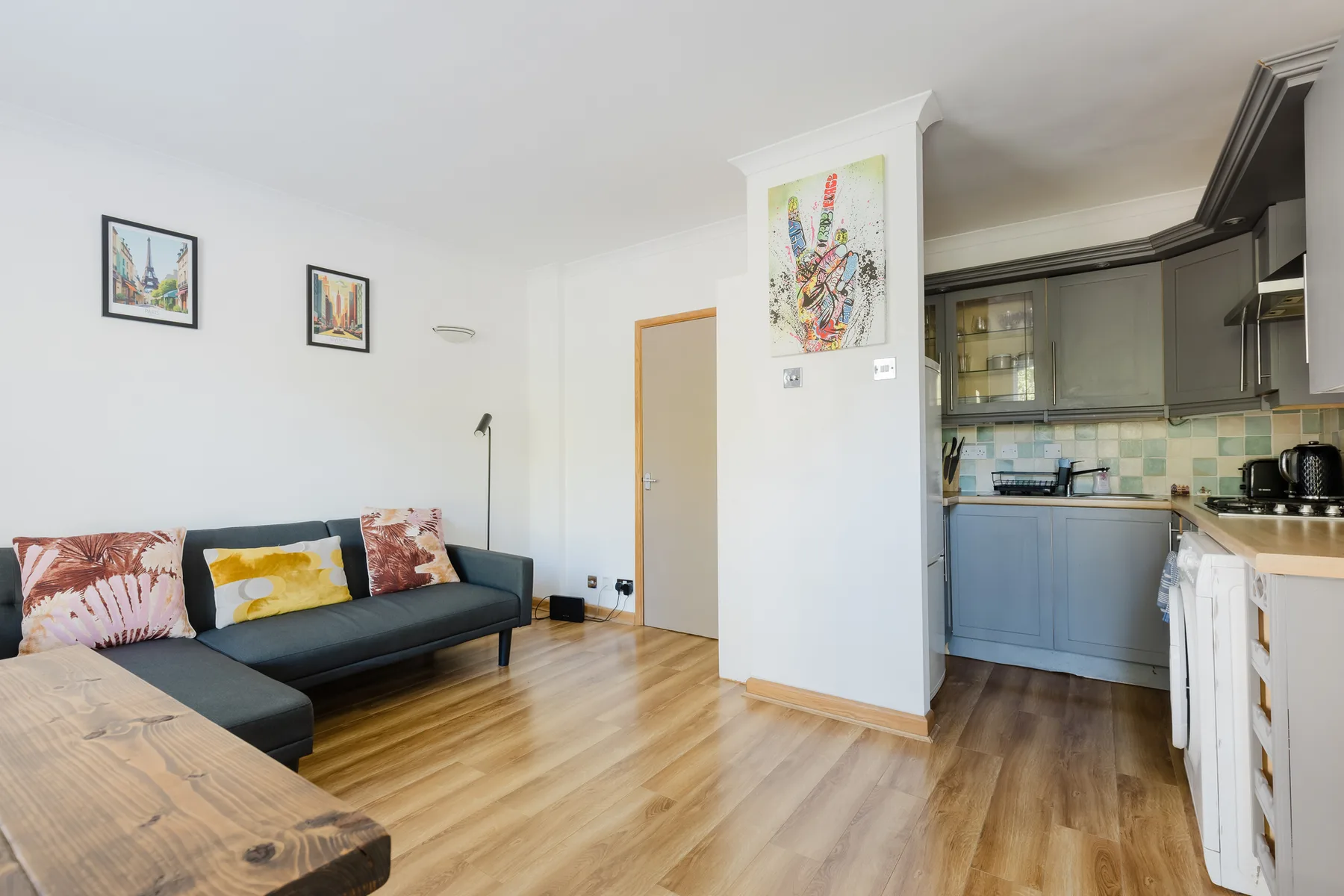 A bright living area with a dark sofa beside an open kitchen.