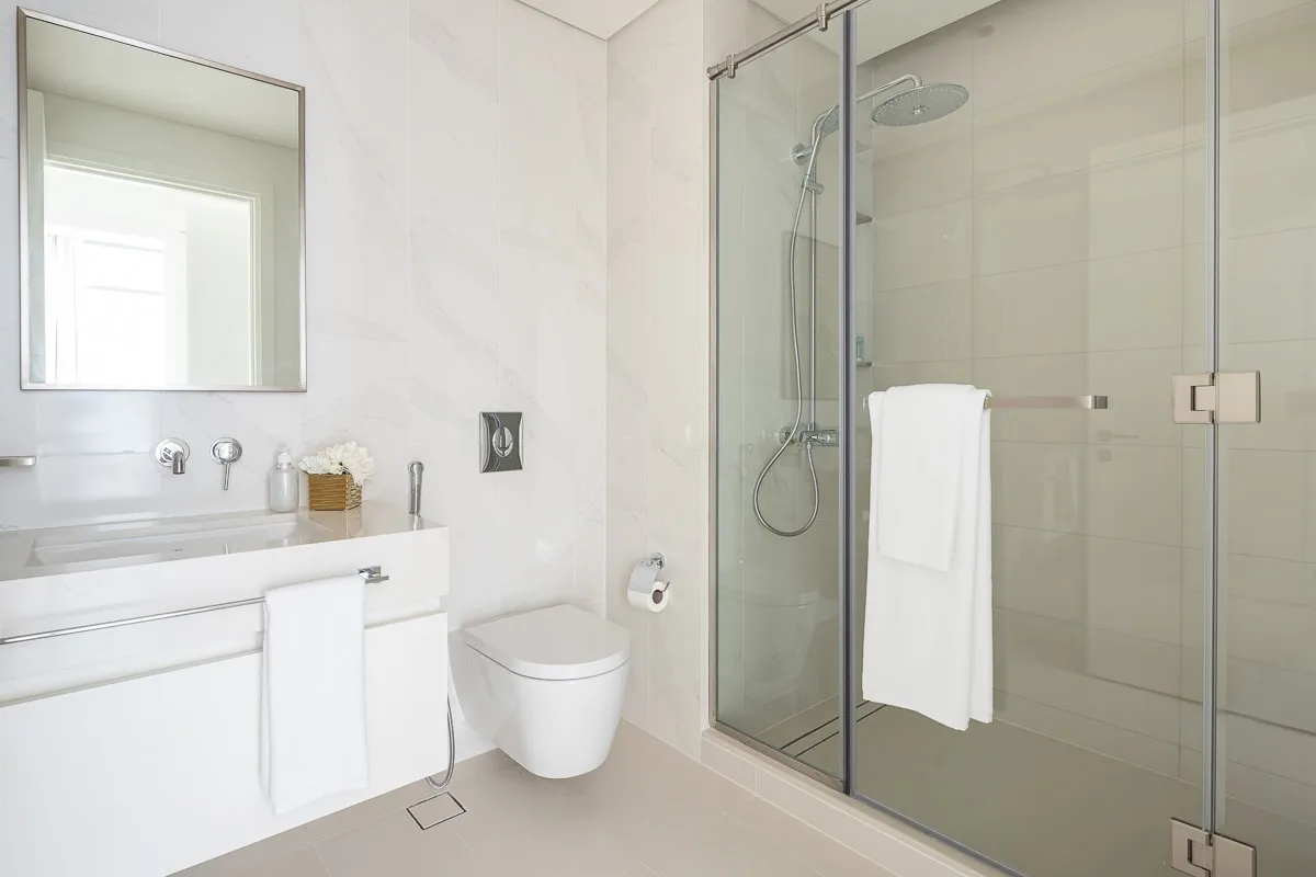 A bright bathroom with a sink, toilet, and glass shower.
