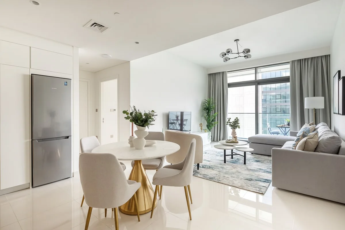 Una luminosa sala de estar y comedor de planta abierta, con una ventana amplia y muebles neutros.