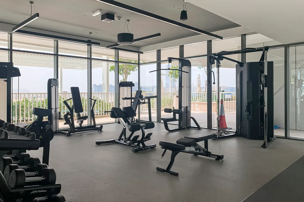 A gym with exercise machines and large windows overlooking the city.