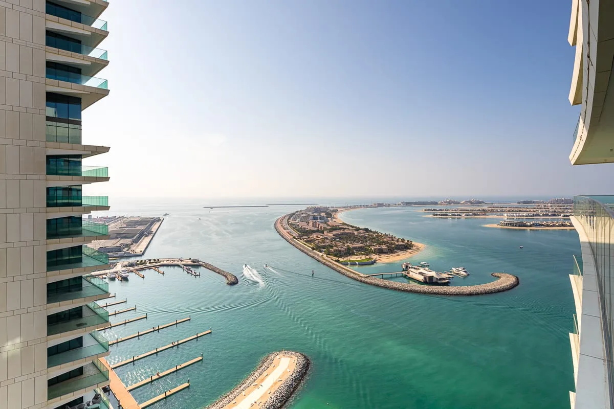 A coastal bay with a curved island and waterways, viewed between high-rise buildings.