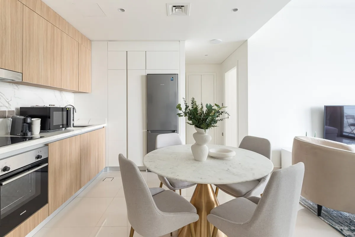 A bright open-plan kitchen and dining area with a round table and neutral seating.