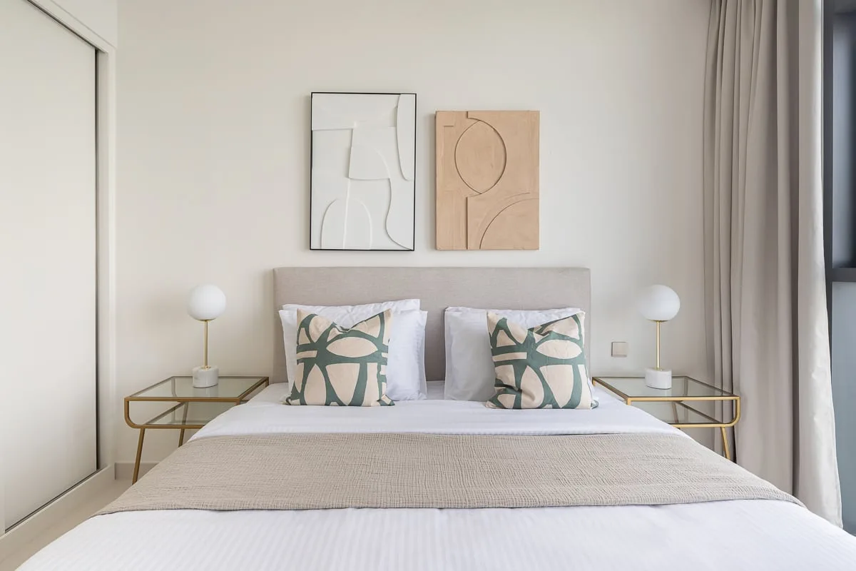A bright bedroom with a neatly made bed and matching bedside tables.