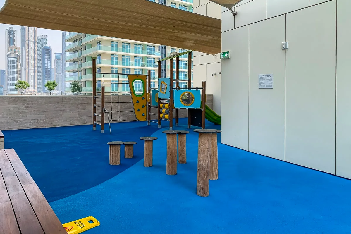 A rooftop playground with blue flooring and colorful play equipment.