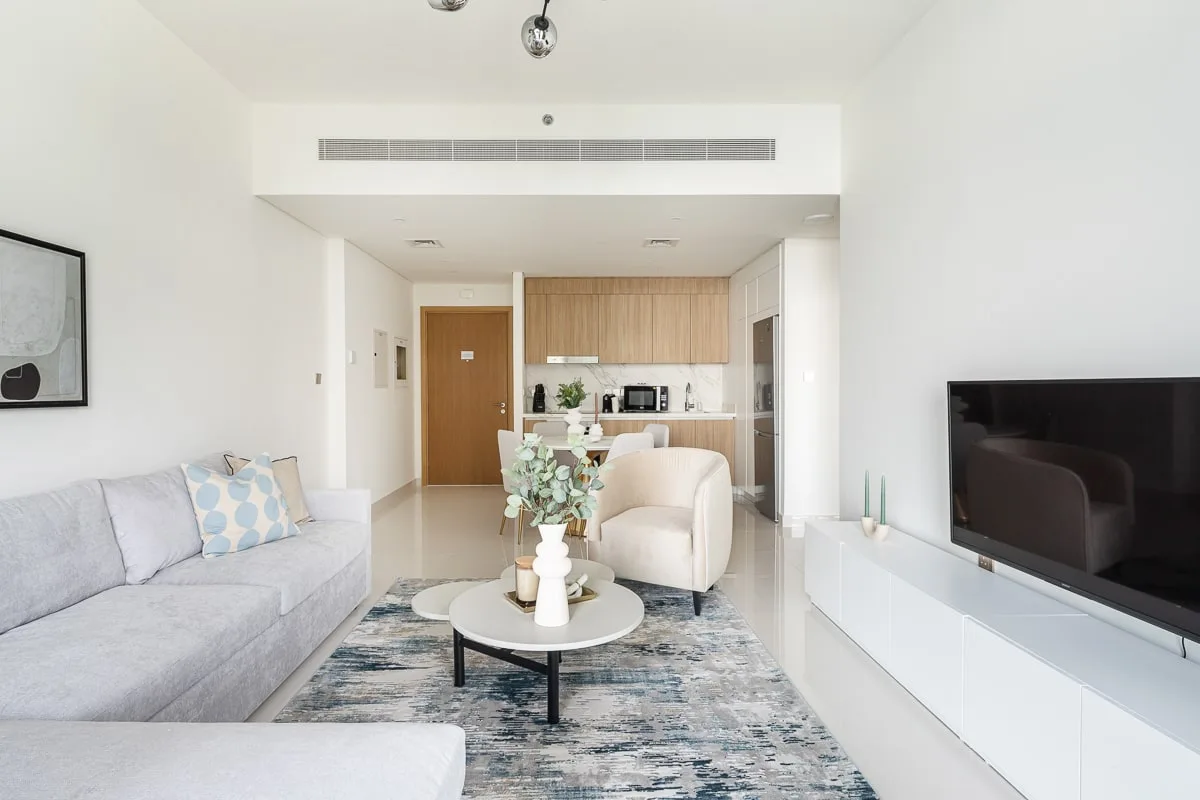 A bright living room with seating, a coffee table, and a television.