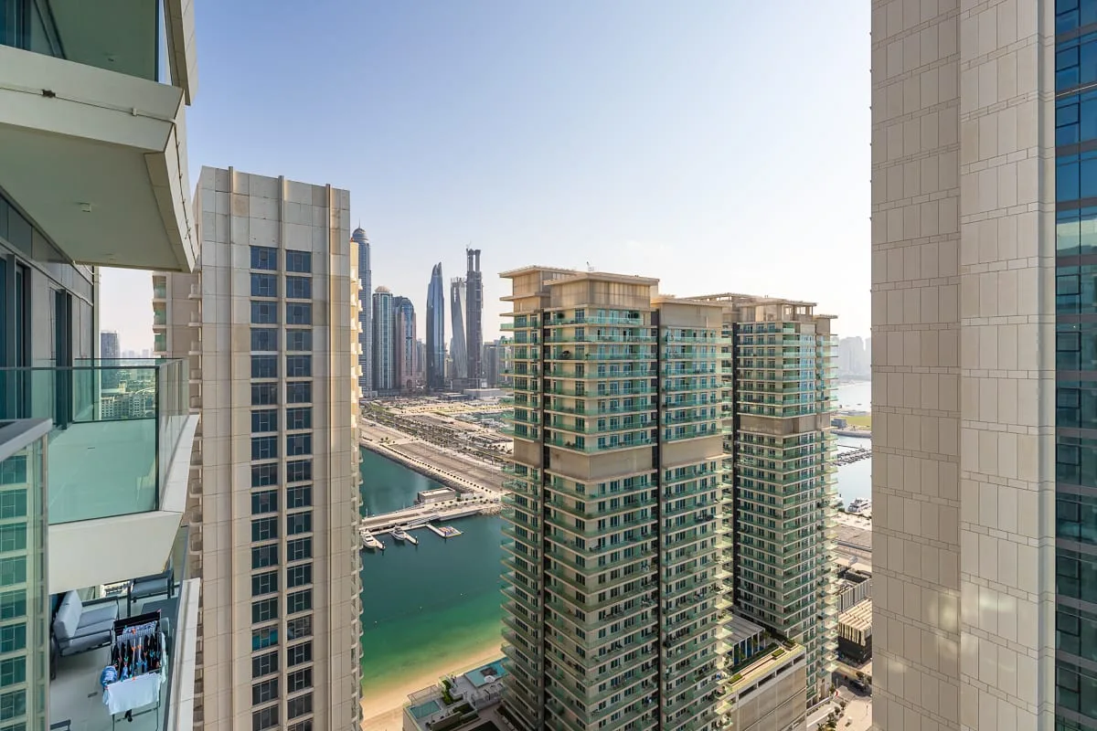 A city skyline rises beyond modern high-rise buildings and a waterfront.