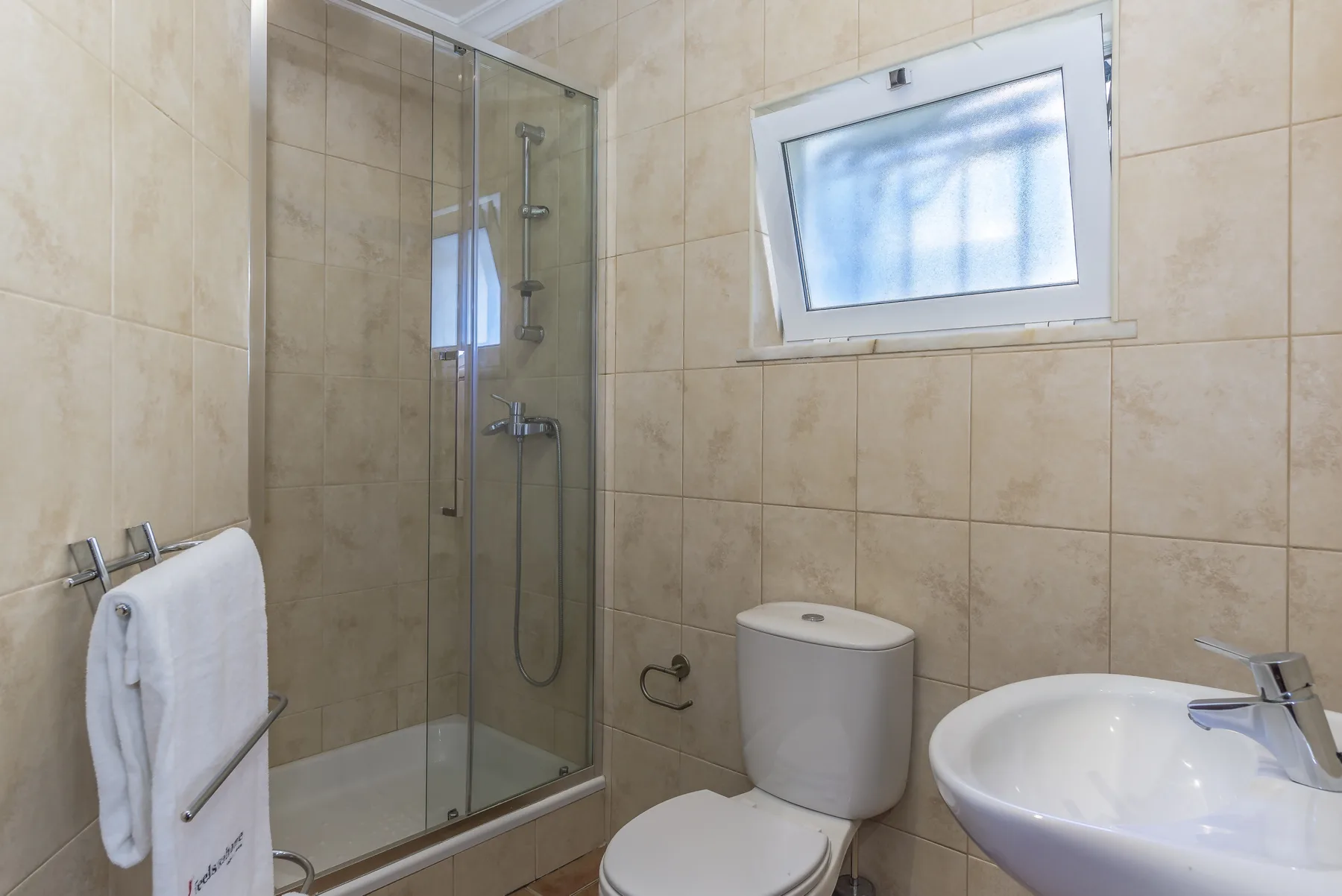 Un baño alicatado con ducha, inodoro y lavabo.