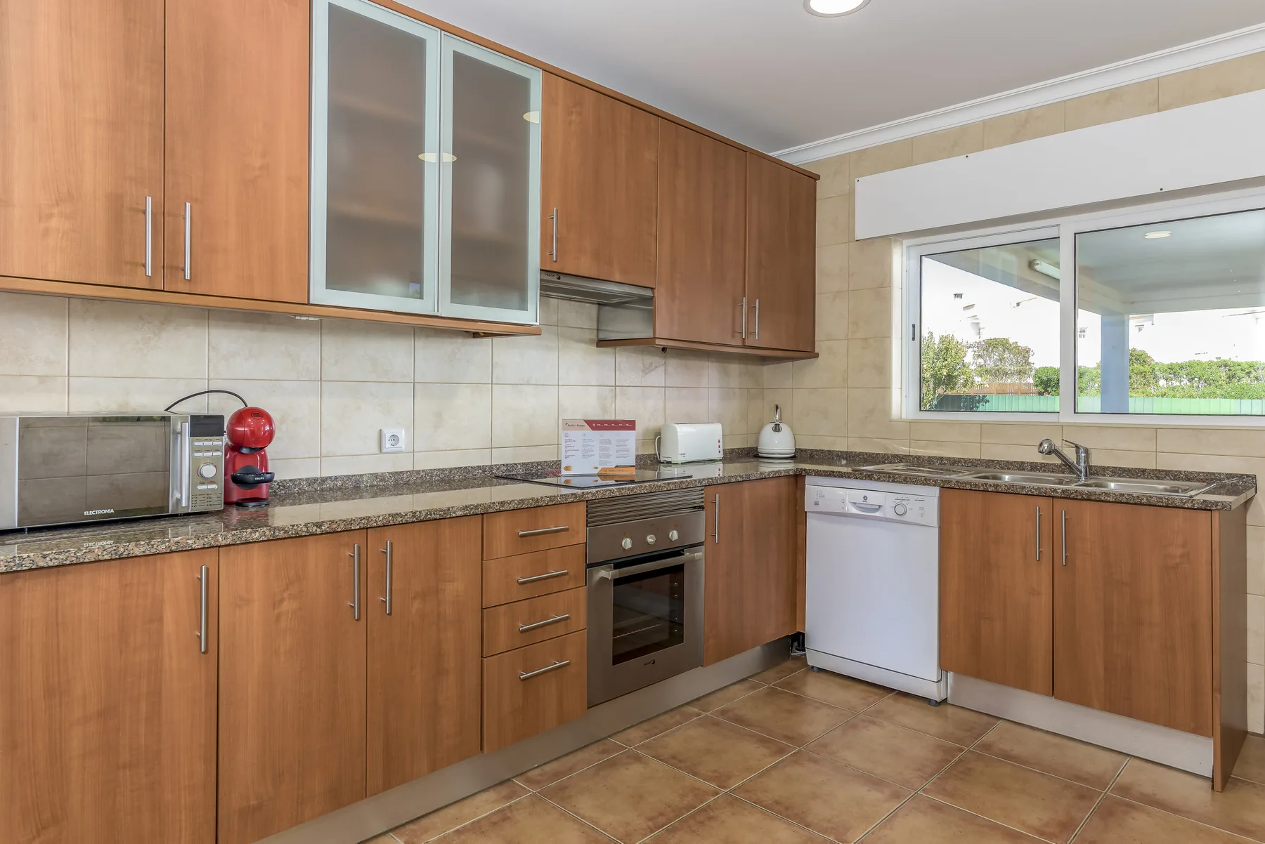 Una cocina con armarios de madera, una encimera y una ventana.