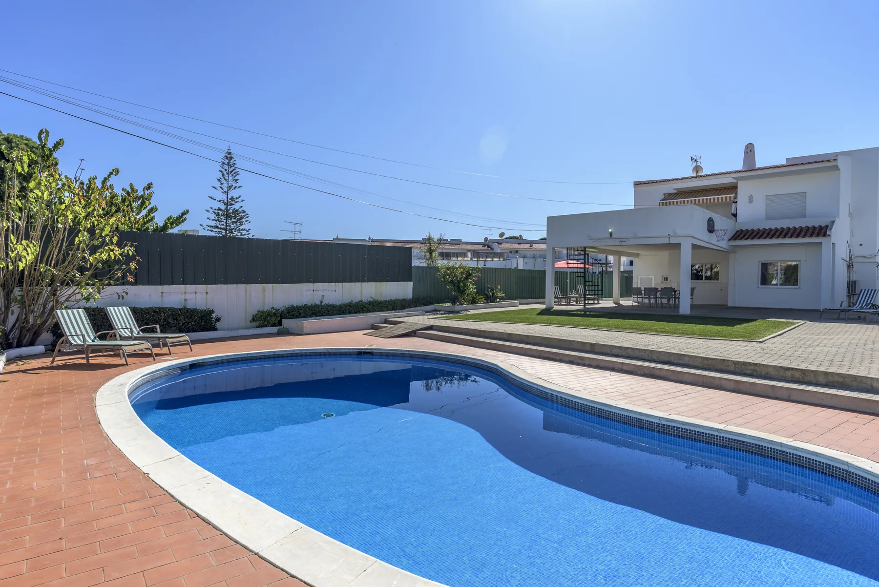 Una piscina al aire libre junto a un patio pavimentado y una casa moderna.