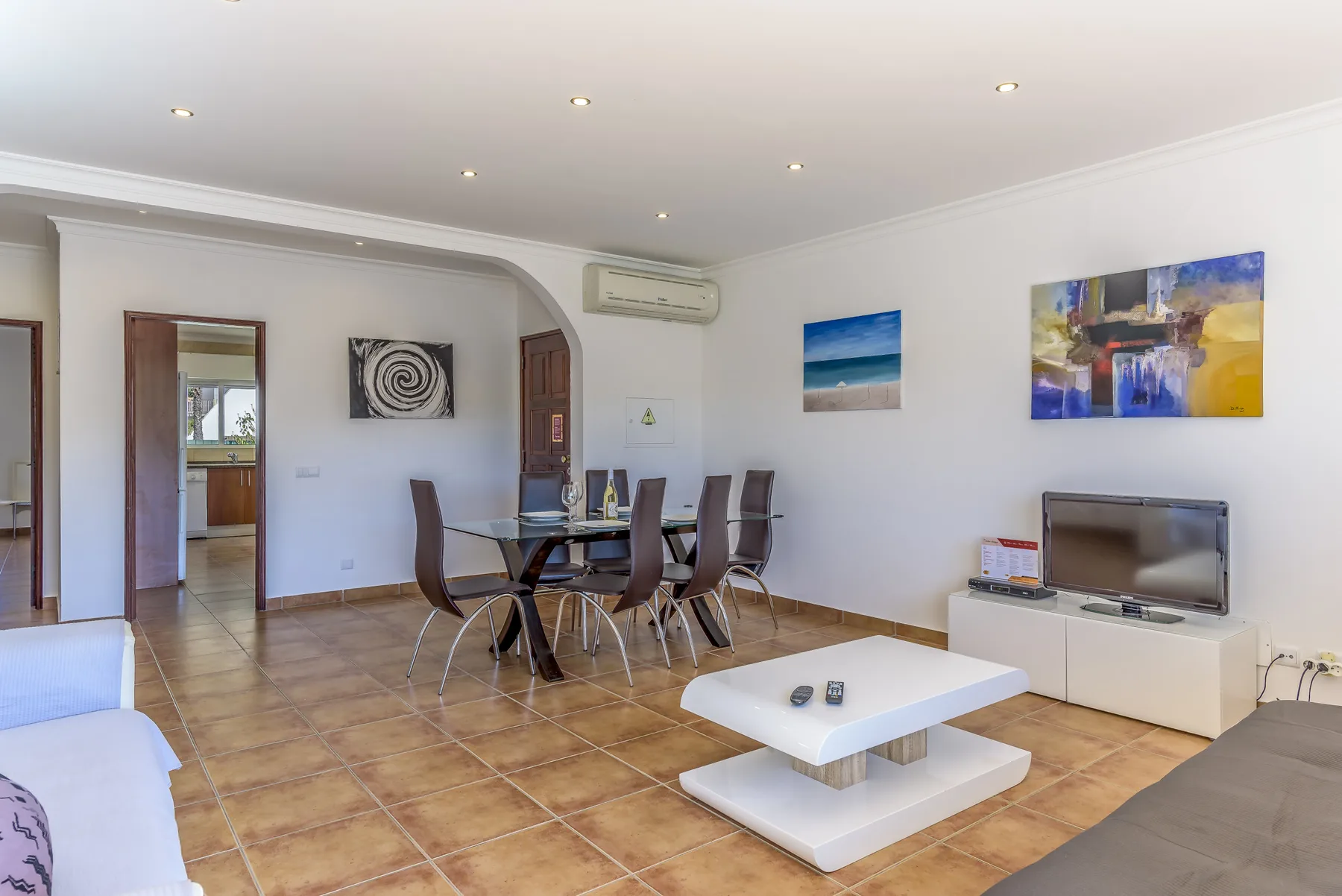 Una sala de estar y comedor con un televisor y cuadros en la pared.