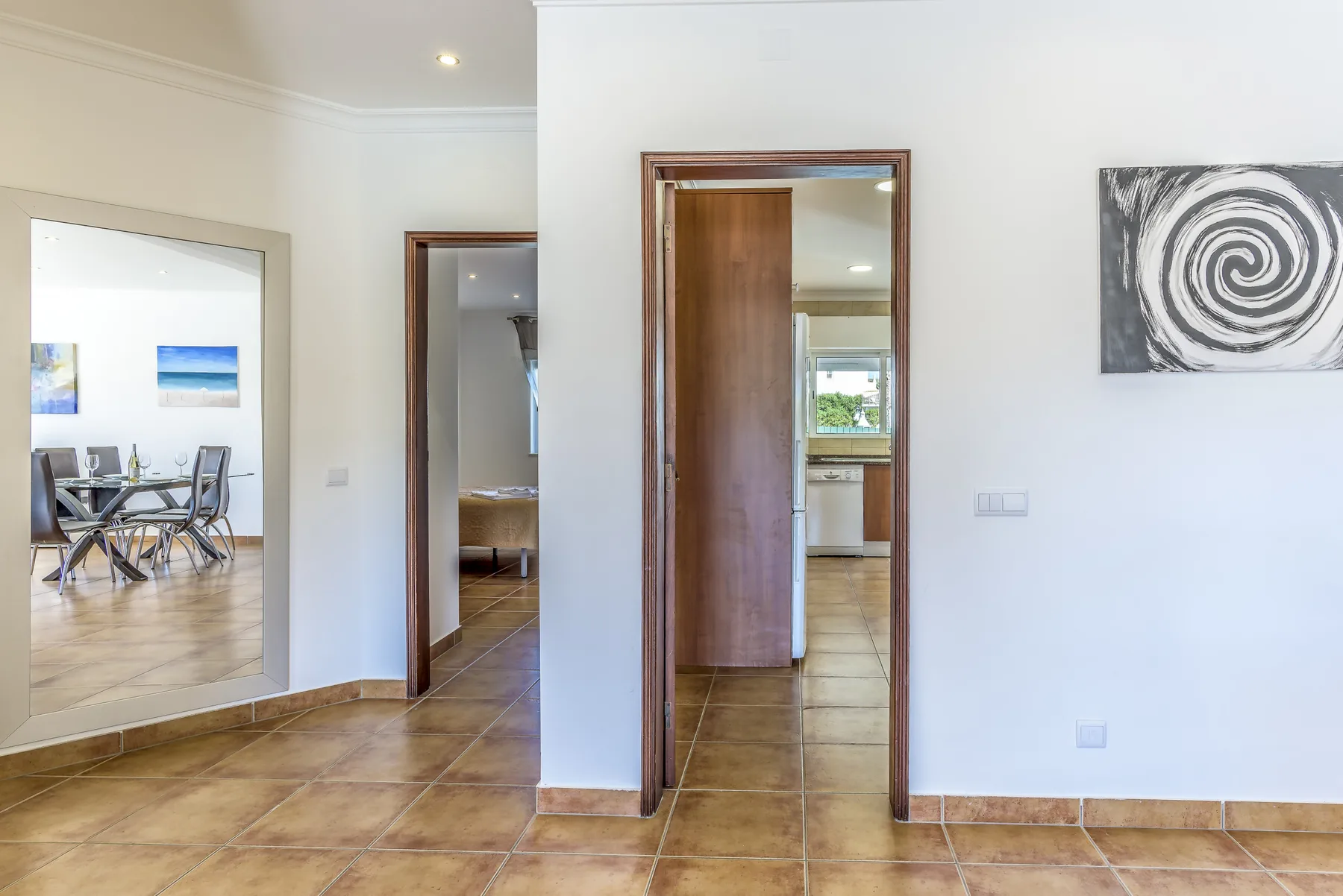 Un pasillo interior luminoso conecta varias habitaciones con suelo de baldosas.