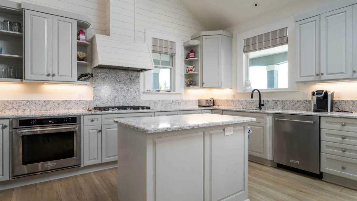 Una cocina luminosa con una isla central, gabinetes claros y electrodomésticos de acero inoxidable.