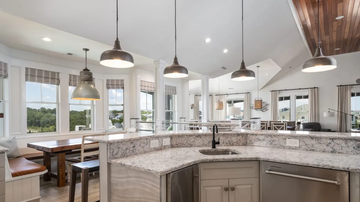 Una cocina luminosa con una gran isla, asientos junto a la barra y ventanas.
