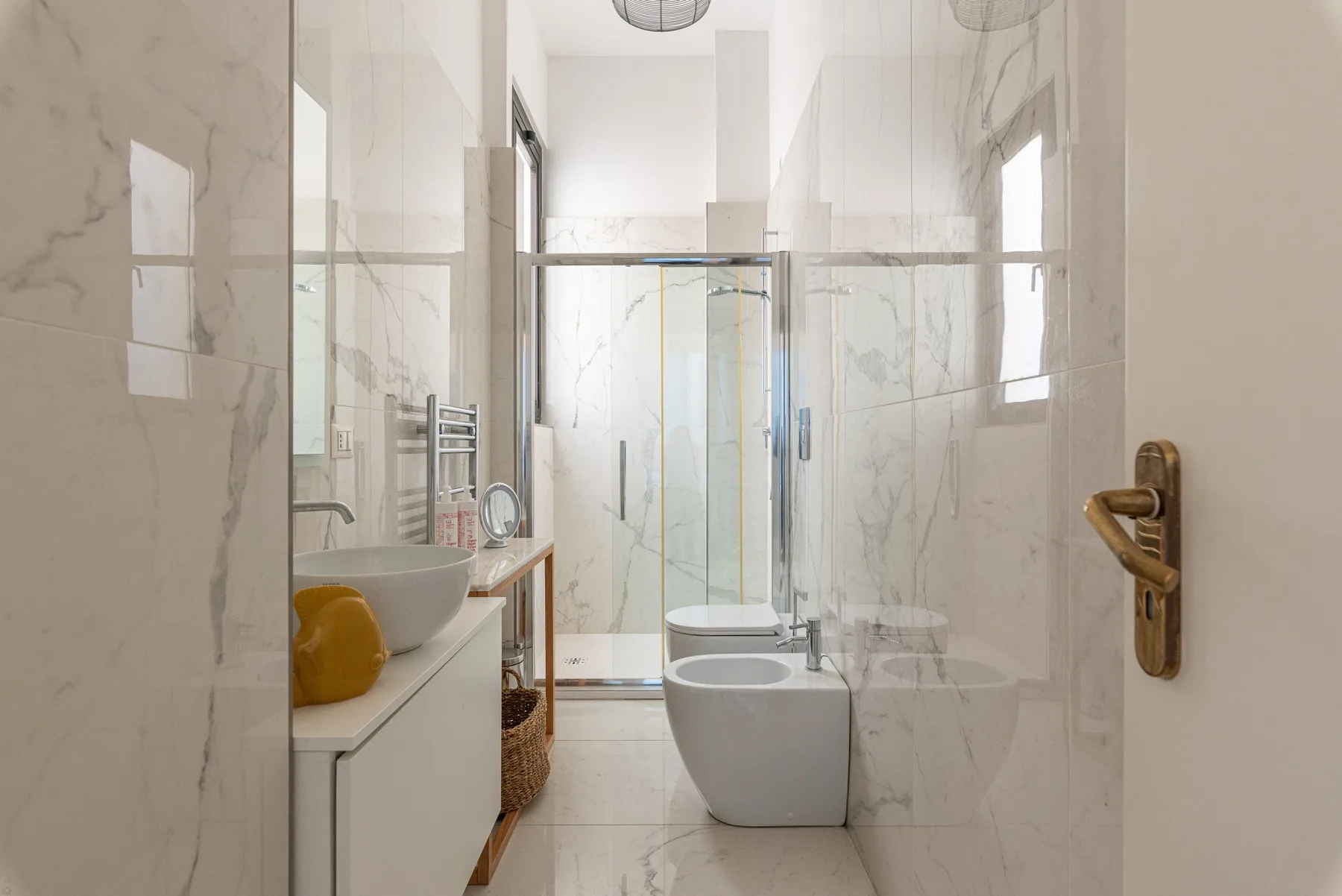 A bright tiled bathroom with a glass shower and white fixtures.