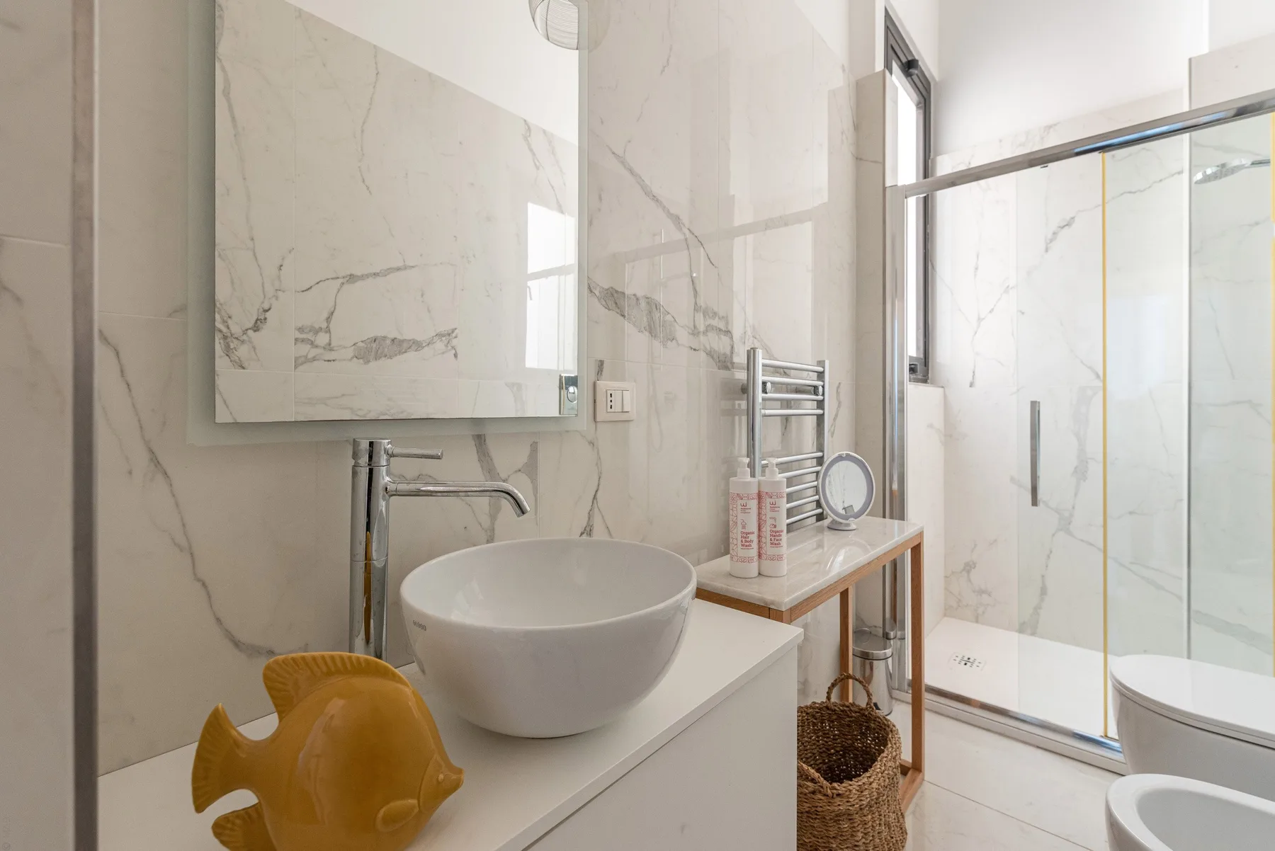 Un baño luminoso con lavabo sobre encimera y ducha con mampara de vidrio.